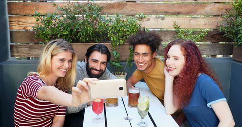 Young Adults Enjoying Outdoor Gathering with Drinks and Selfie