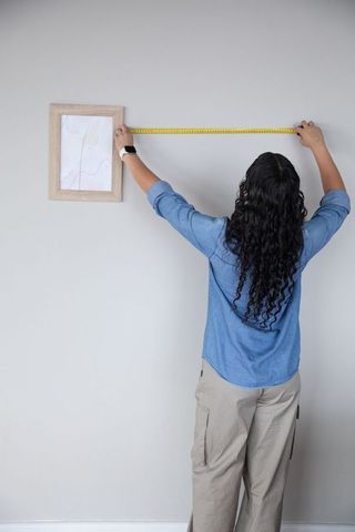 Woman Measuring Wall for Home Decor with Tape