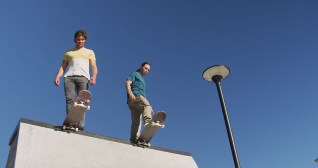 Two male friends skateboarding together on sunny day. hanging out at skate park in summer.