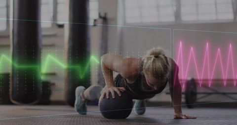 Woman performing medicine ball plank with heart rate data overlay for fitness training
