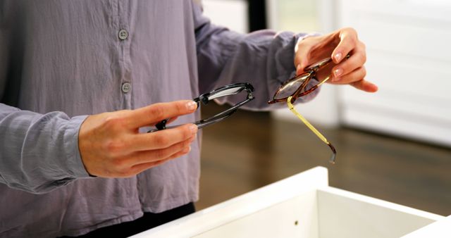 Person Choosing Between Two Pairs of Glasses in Store - Download Free Stock Images Pikwizard.com