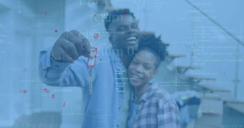 Couple celebrating new home holding keys with digital code overlay for proptech