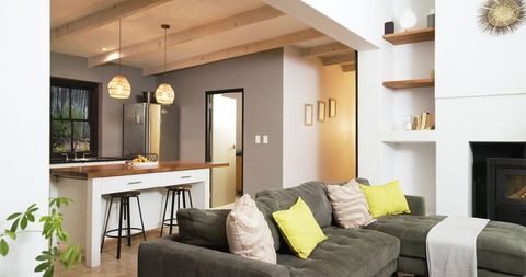 Modern open-plan living featuring l-shaped gray sectional, lime pillows and wood kitchen island