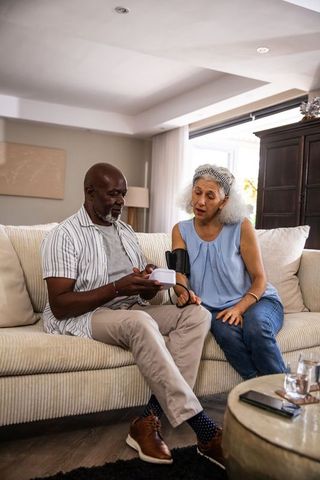 Senior Couple Checking Blood Pressure Together on Sofa