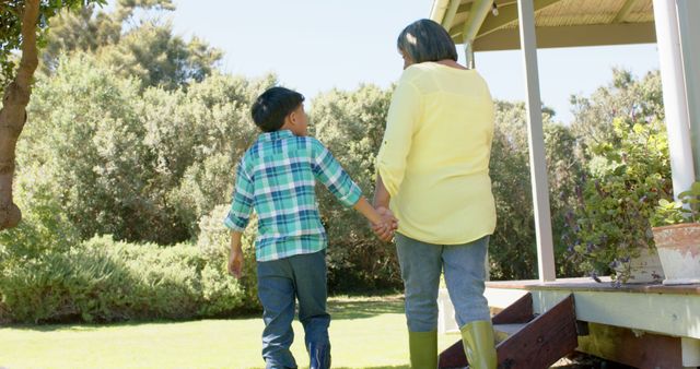 Happy biracial grandmother and grandson walking in sunny garden - Download Free Stock Photos Pikwizard.com