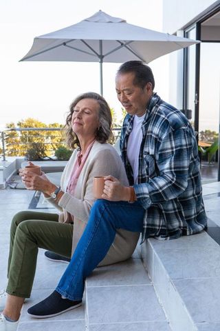 Relaxed Senior Couple Enjoying Coffee Together on Patio Steps