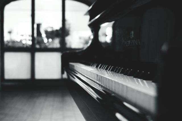 Classic black and white piano close-up in an empty room. Ideal for music-related projects, décor inspiration, artists' portfolios, and blog posts about musical instruments or interiors. Suitable for use in print design, advertisements promoting music classes, and websites dedicated to classical music.
