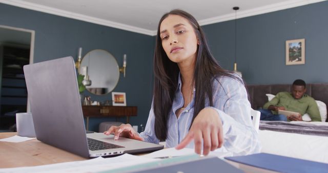 Young Woman Working from Home at Laptop with Partner in Background - Download Free Stock Images Pikwizard.com