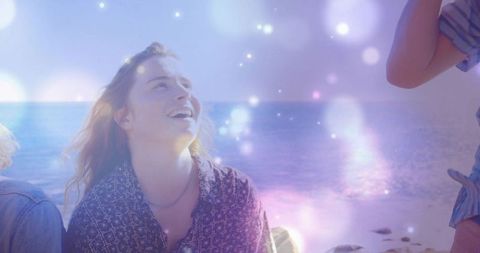 Joyful Woman Relaxing by Sunlit Shoreline with Dreamy Bokeh