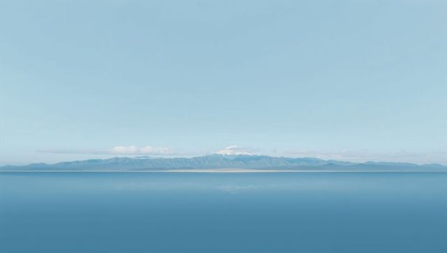 Minimalist seascape with snow-capped peak rising above coastal plain and mirror reflection