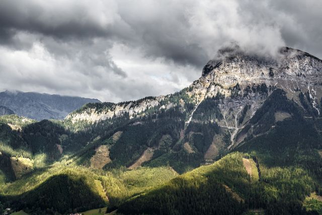 Mountains with forested slopes under a cloudy sky. Terrain looks rugged and majestic. Great for promoting travel, outdoor adventures, and photography materials. Ideal for websites, brochures, and posters focused on nature, hiking, and wilderness exploration.