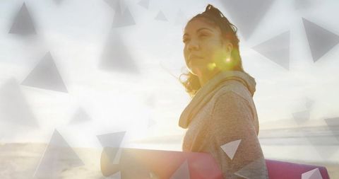 Woman Holding Yoga Mat on Beach at Sunset with Abstract Motifs