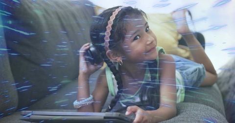 Young girl listening to music on tablet while lounging on couch, relaxed home lifestyle