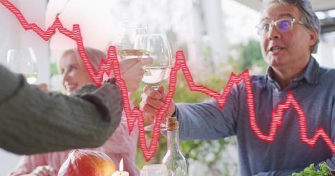 Alfresco toasting and clinking wine glasses with red market graph overlay on outdoor gathering