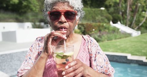 Senior Woman Relaxing Poolside Enjoying Refreshing Cocktail