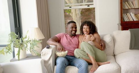 Happy Couple Relaxing with Popcorn and Coffee at Home
