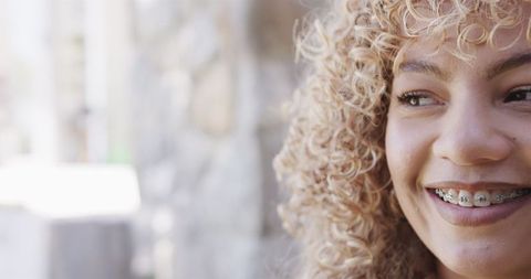 Young Woman Smiling with Braces and Curly Hair Outdoor Close-Up