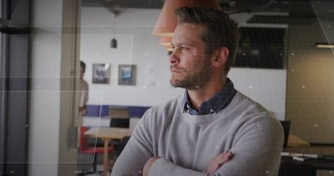 Thoughtful professional contemplating strategy with arms crossed in modern open-plan office