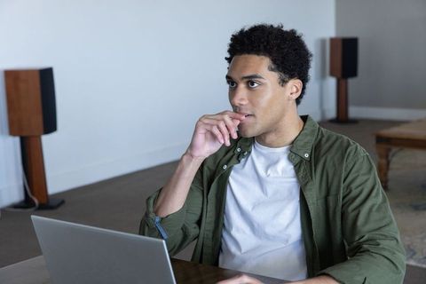 Thoughtful african american man using laptop in casual living room