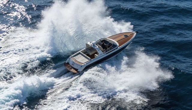 Luxury speedboat cutting through deep blue ocean waves with teak deck and skipper steering