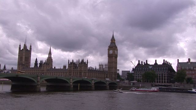 Shows iconic landmarks Big Ben and Westminster Abbey in London on a cloudy day. River in foreground with a bridge connecting. Great for travel promotions, educational material, and illustrating British culture.