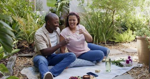 Diverse Couple Toasting During Outdoor Picnic in Serene Garden