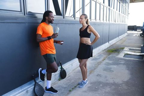 Man and Woman Discuss Holding Padel Rackets on Rooftop