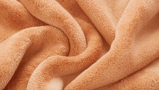 Plush peach fleece blanket showcasing soft dense pile and cozy folds