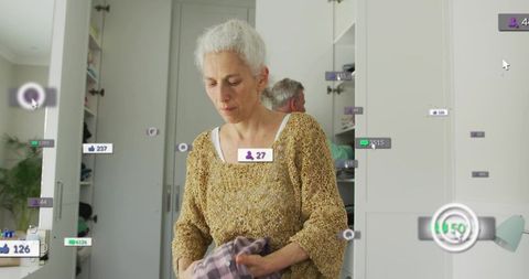 Mature woman organizing closet with ar labels folding clothes for home organization