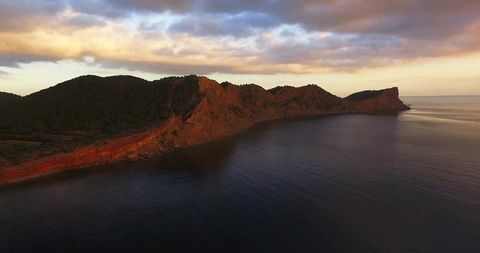 Dramatic Rocky Cliffs at Sunset over Tranquil Ocean