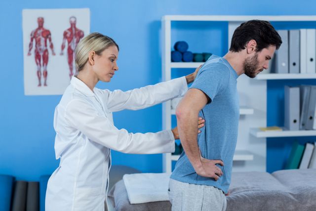 Physiotherapist examining man's back in a clinic setting. Useful for illustrating healthcare, physical therapy, rehabilitation, and medical treatment concepts. Ideal for articles, blogs, and promotional materials related to wellness, pain relief, and physiotherapy services.