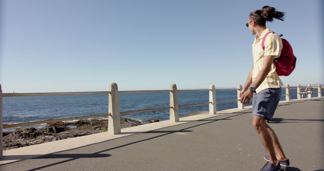 Young man skateboarding along seaside boardwalk on a sunny day - Download Free Stock Images Pikwizard.com