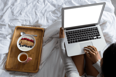 Transparent screen laptop by bedside breakfast tray at home