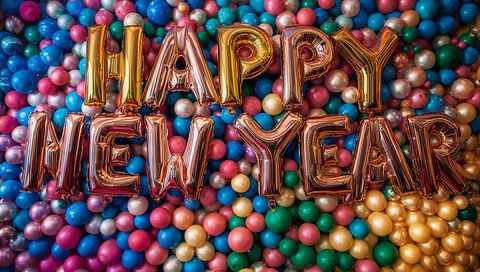 Rose gold happy new year foil letter balloons over colorful glossy latex balloon wall