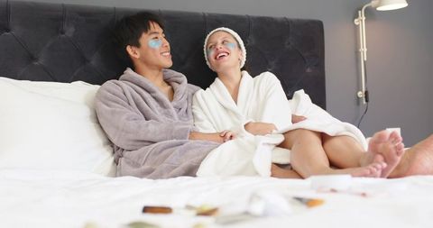 Asian man and white woman enjoying cozy spa night with under-eye patches