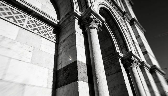 Dramatic black and white architecture showing corinthian columns, rounded arches, carved frieze