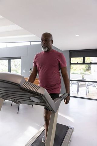 Senior exercising on treadmill in modern home gym