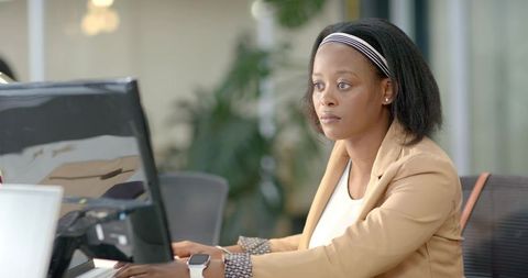 African American businesswoman working at desktop computer in modern office focusing on screen