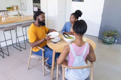 African american family sharing healthy salad at round table in modern kitchen