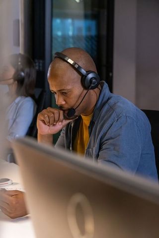 African american customer support agent wearing headset concentrating at workstation