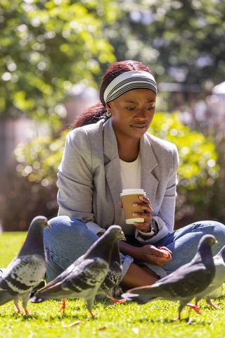 Relaxing urban park moment watching pigeons while holding takeaway coffee