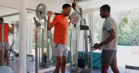 Man Lifting Weights with Guidance in Home Gym