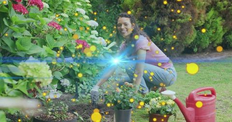 Smiling female gardener kneeling, planting flowering pots and watering with red can