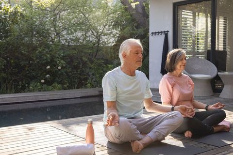 Senior Couple Practicing Meditation Poses on Backyard Deck
