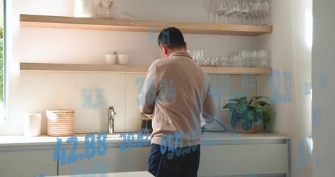 Mature asian man making coffee in minimalist modern kitchen with blue data overlays