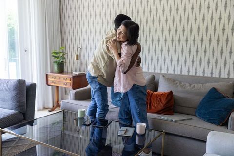 Asian woman and african american man embracing on sofa, cozy living room warmth