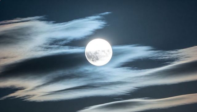 Glowing Full Moon Revealing Lunar Surface Detail Behind Wispy Clouds and Night Halo