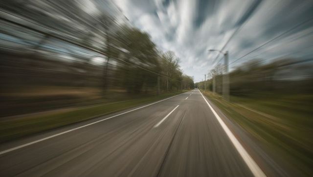 Speeding along empty country road toward vanishing horizon with motion blur and perspective