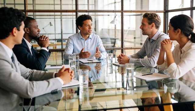 Business leader presenting strategic plan to diverse team around glass conference table