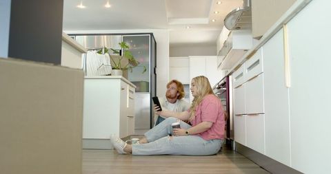 Couple Relaxing in New Home Kitchen with Coffee and Smartphone